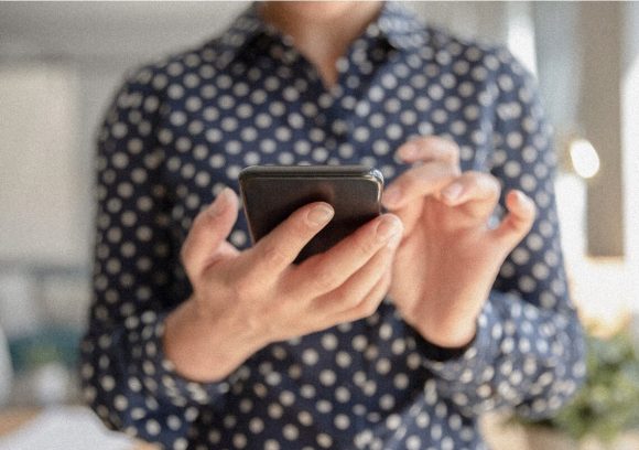 A person holds their phone in front of them while preparing to type. Close up.