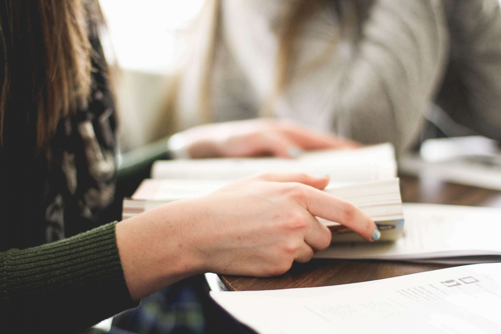 Person reading a book at a table. Close-up.