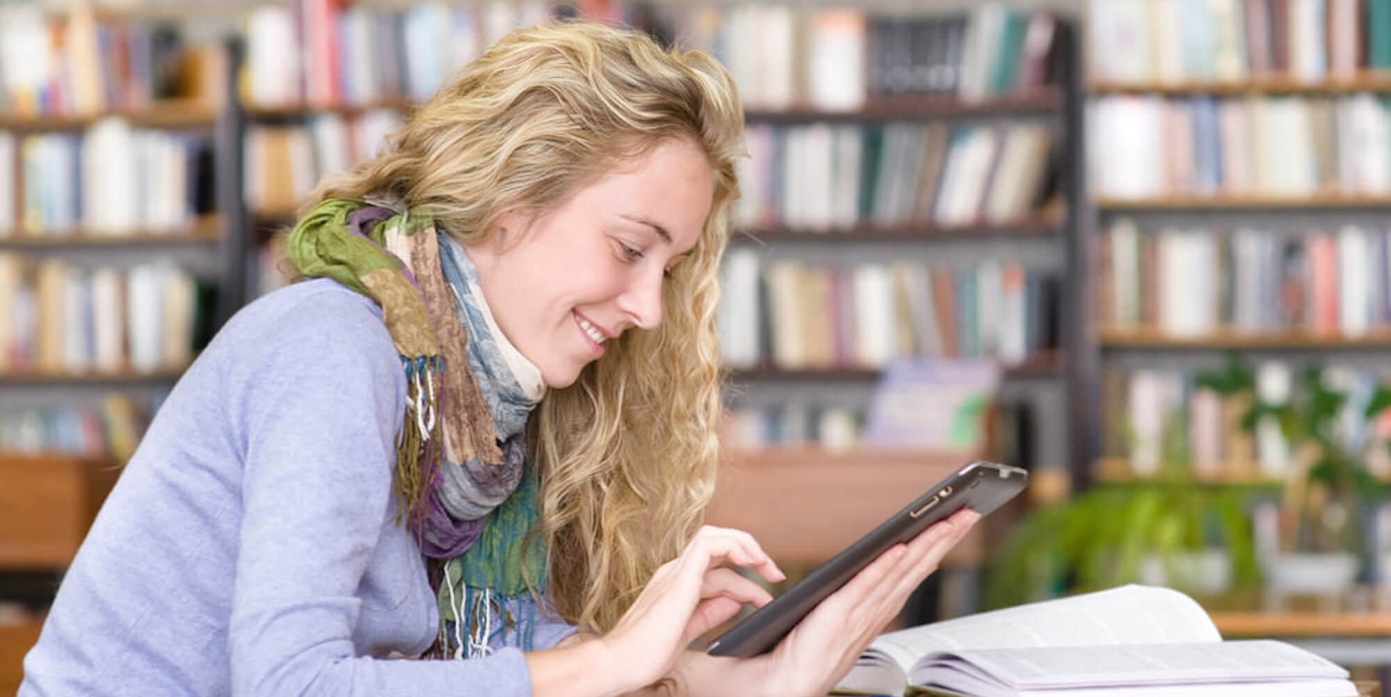 A person working on a tablet while sitting in a library.