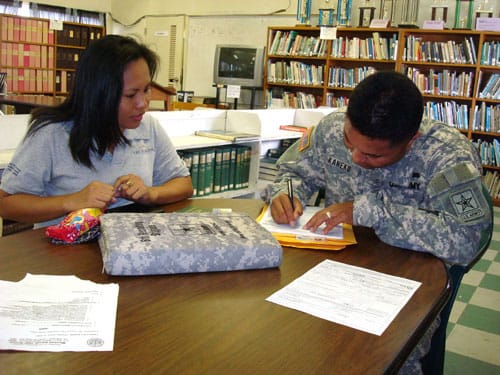 A military person filling out a form on a desk in a library.