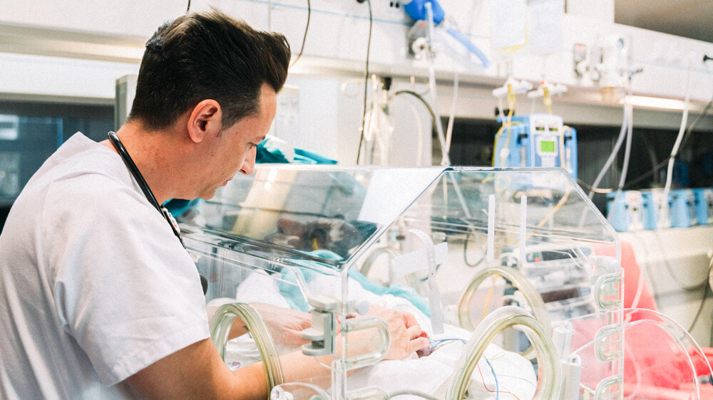 A RN cares for a baby in an incubator.