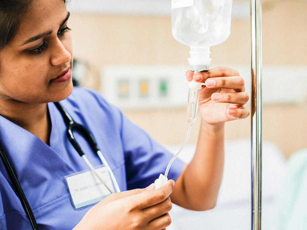 A nurse practitioner hangs an IV drip.