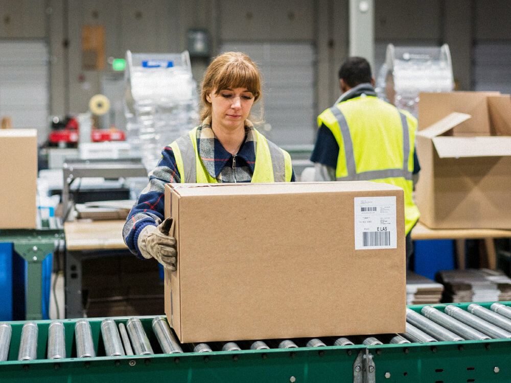 A person inspects a box on an assembly line.