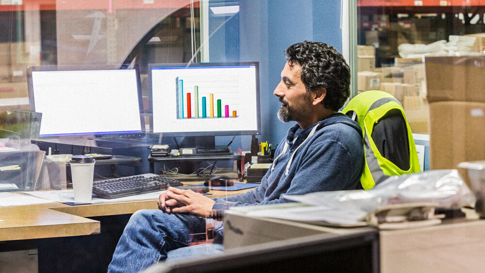 A person sits at a desk in a warehouse office space.