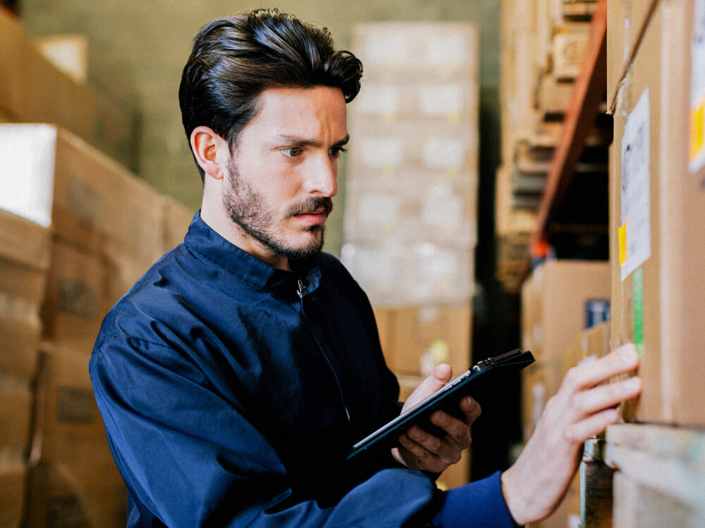 A person checks and compares a label on a box with a tablet.