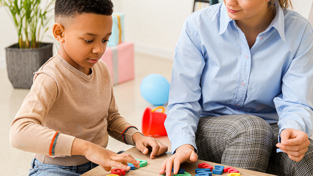 Social worker works with a child client at a low table.