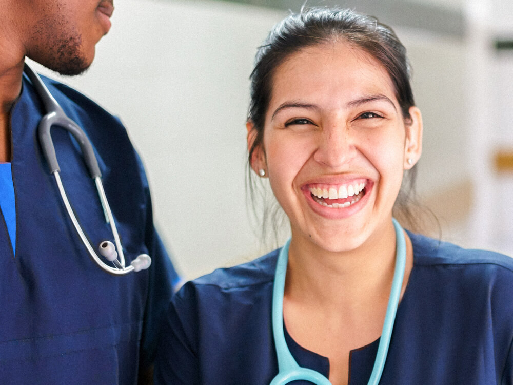 A nursing student smiles next to a fellow student.