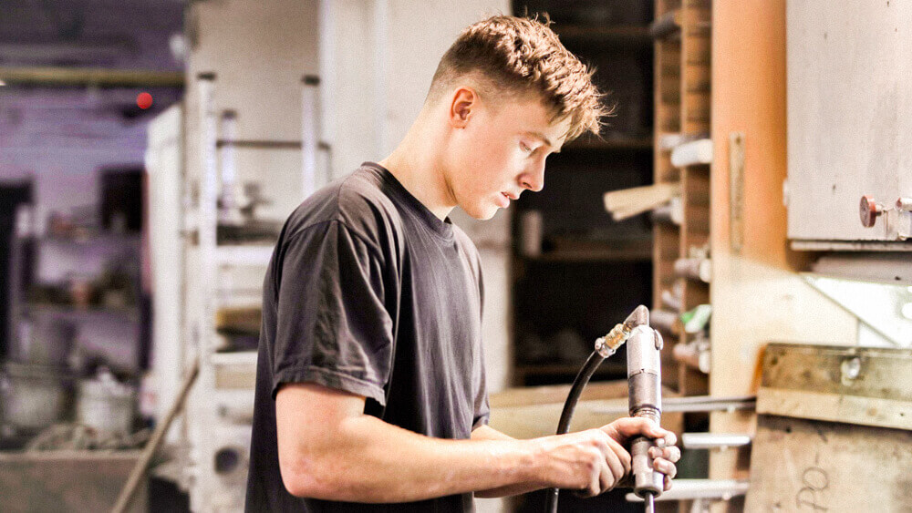 Automotive mechanic holding a tool in a shop.