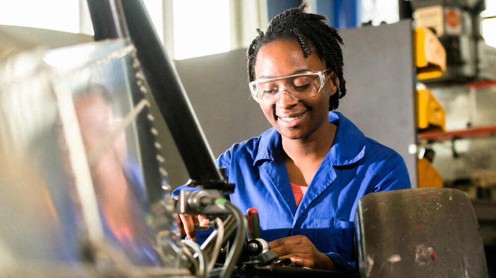 Automotive mechanic working in a shop and wearing safety glasses.