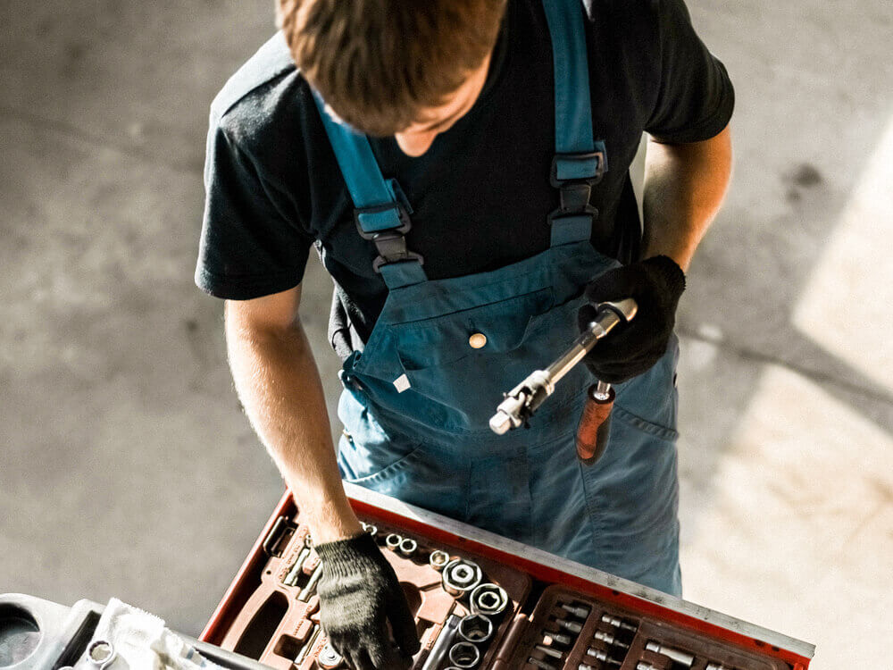 Automotive mechanic pulling sockets from a socket set in drawer.