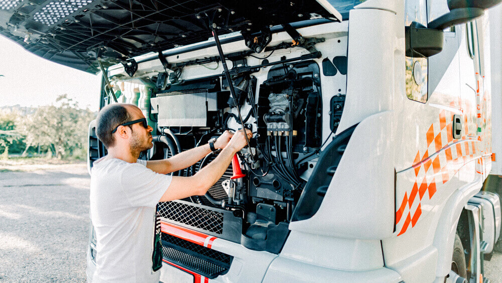 Automotive mechanic working under the hood of a semi truck.