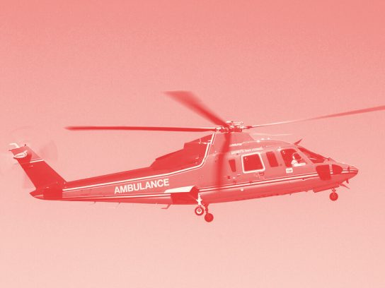 A red medical helicopter flying in a blue sky.