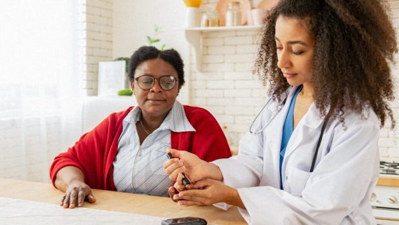 A diabetes care specialist pricks the finger of a patient.