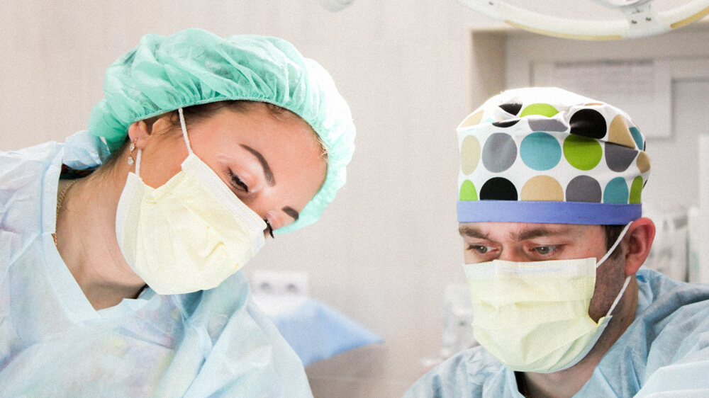 Two nurses assist in surgery.