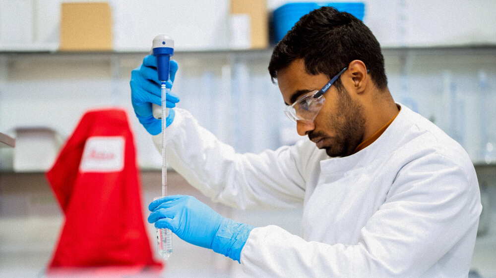 A person measures liquid in a lab.