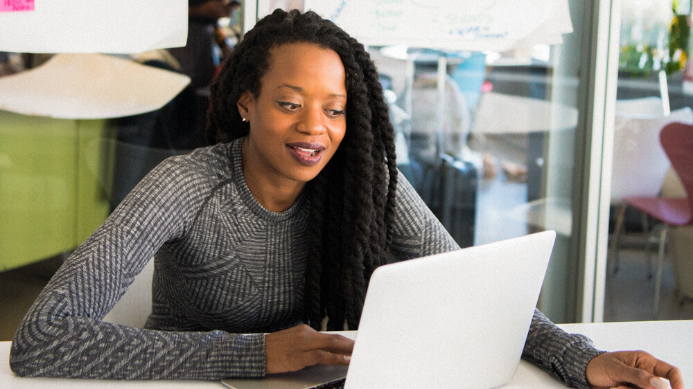 Advanced security practitioner works on a laptop in a modern office space.