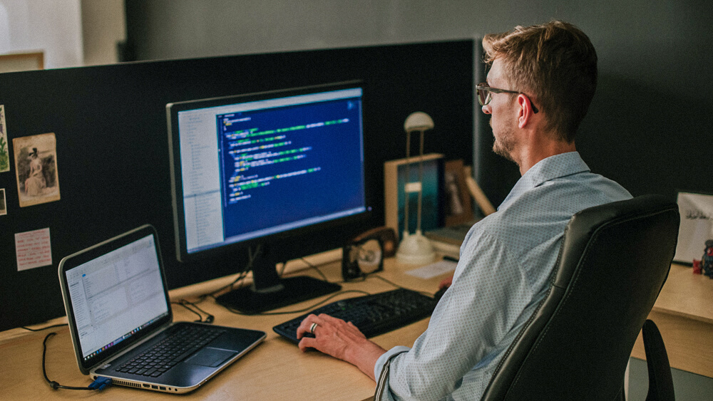 Penetration tester works at their desk with one hand on the keyboard as they look at their monitor.