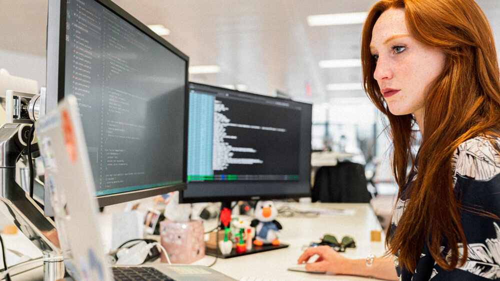 An ethical hacker works from their desk in a corporate office.