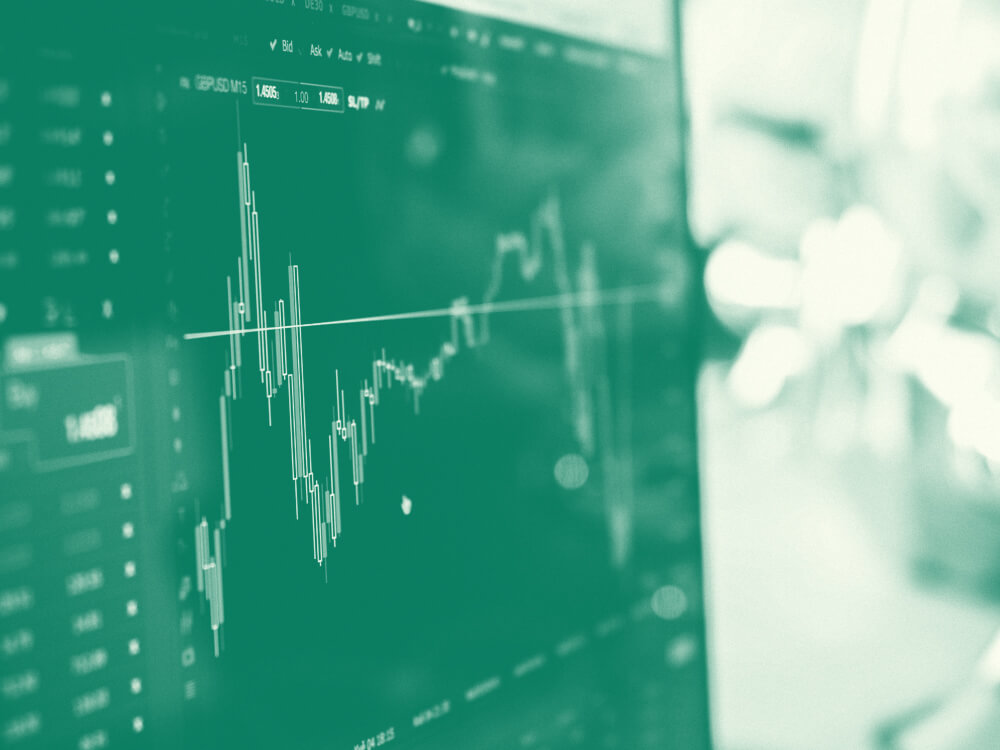 Financial securities expert holds a pen in one hand and enters numbers into a computer with other hand.