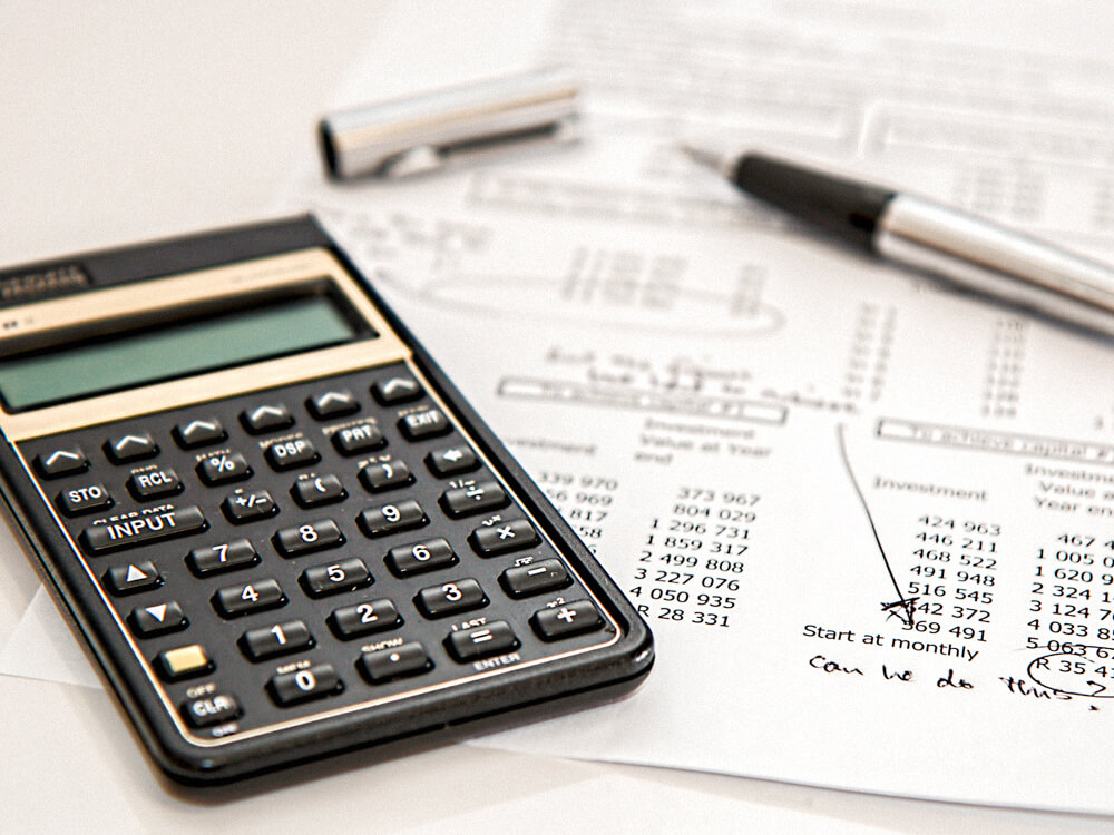 Calculator and pen on top of an investment report on a table.