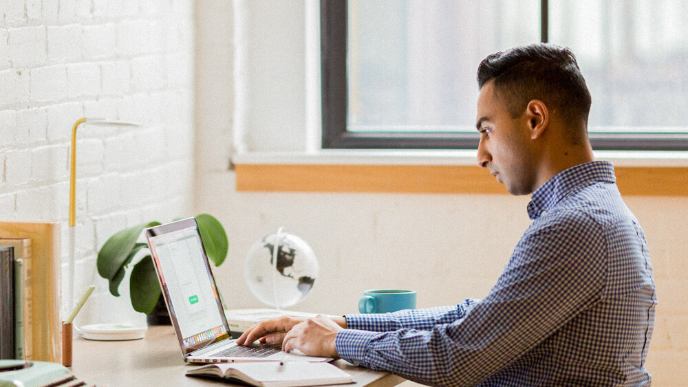 A series six certified financial advisor works at a desk on a laptop.