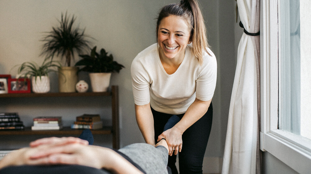 A physical therapist assistant massages the lower leg of a patient.