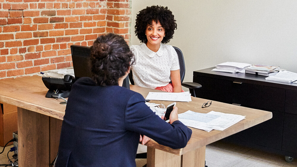 An HR professional meets with an employee in their office.