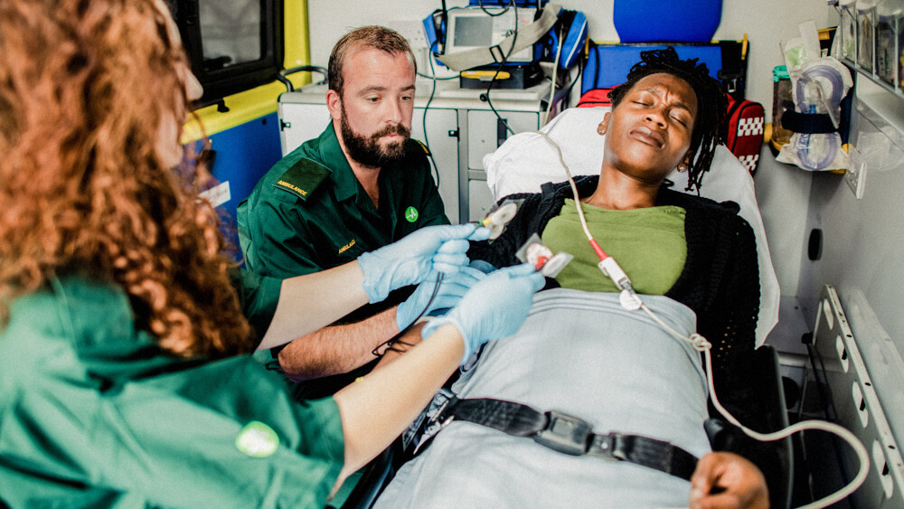 Two paramedics care for a patient inside an ambulance.