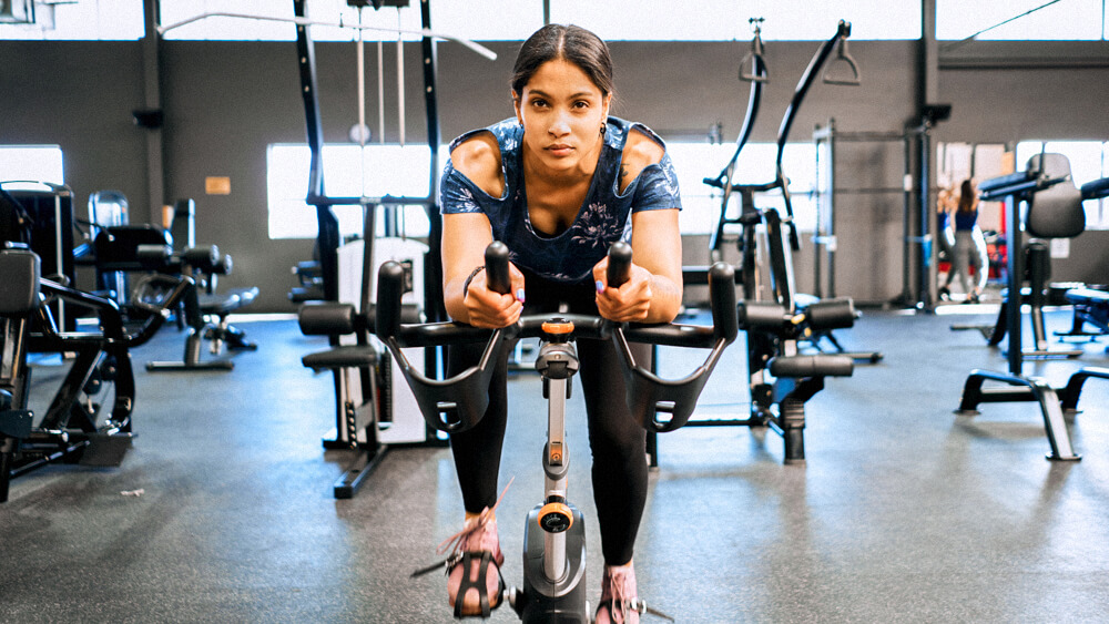 A person trains on a stationary bike in a gym.