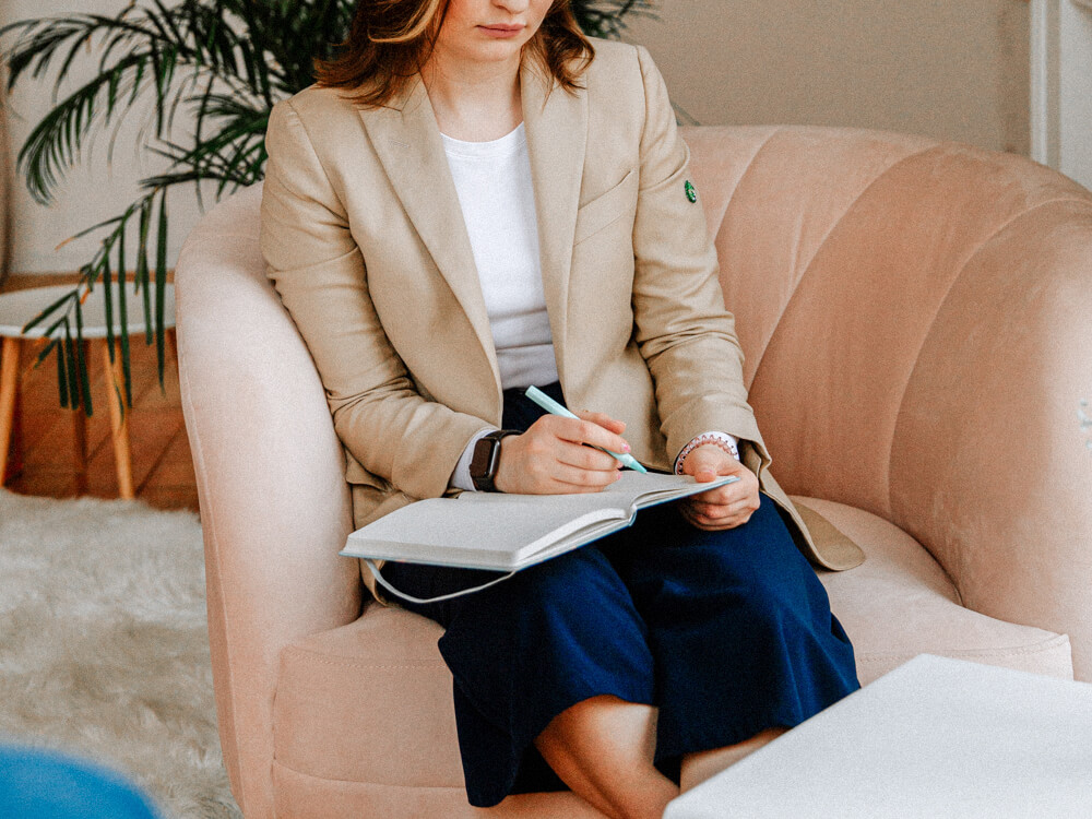 Counselor sits in a chair taking notes.