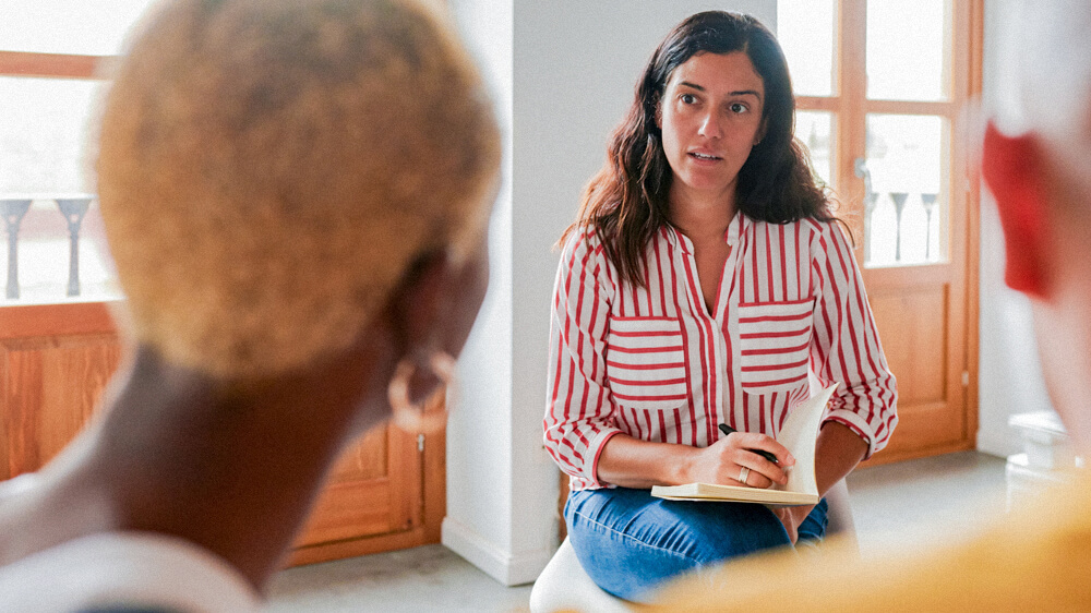 Counselor listens to a couple sitting in front of her and takes notes.