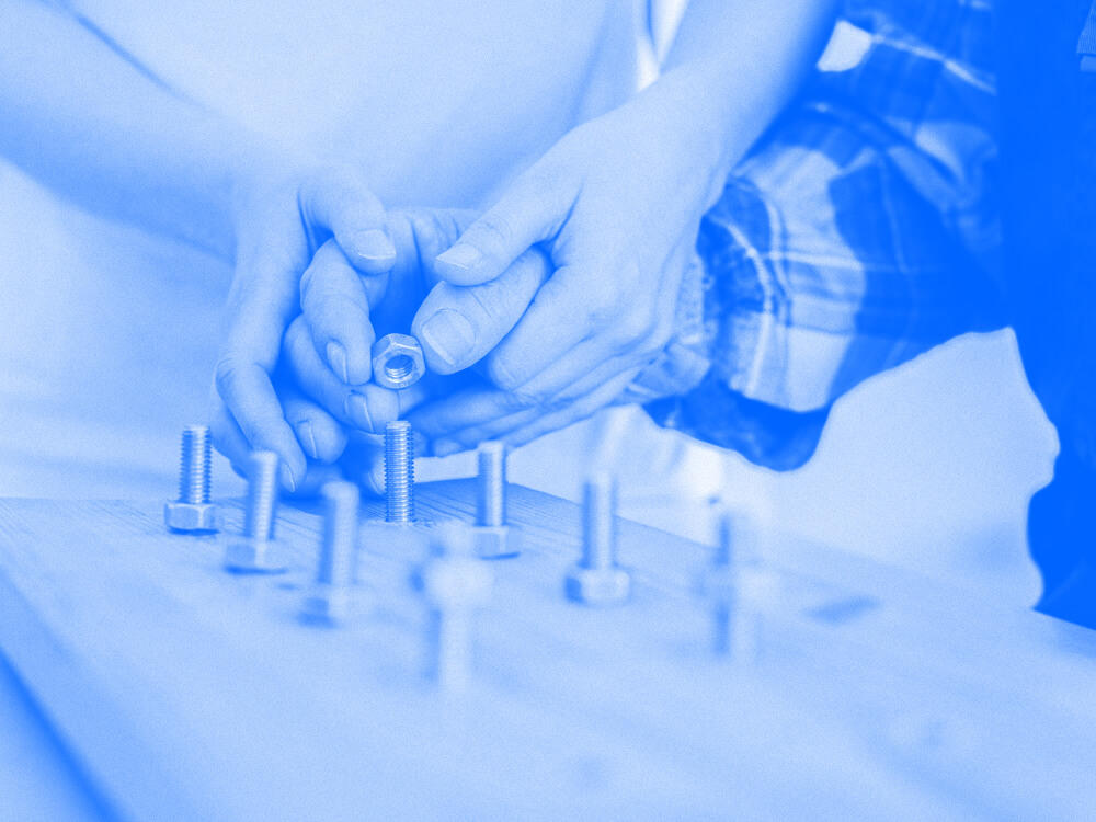 An OT assistant works with a patient on dexterity usings nuts and screws.