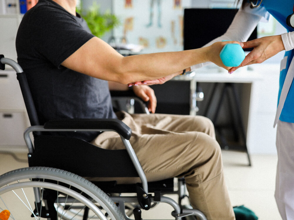 An occupational therapist does exercises with a patient in a wheelchair.