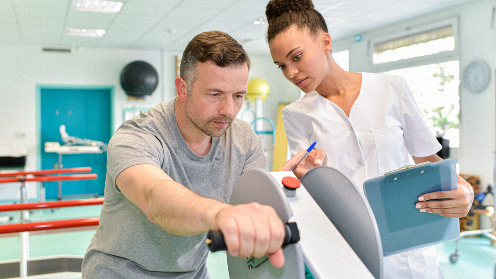 An occupational therapist works with a patient on arm strength.