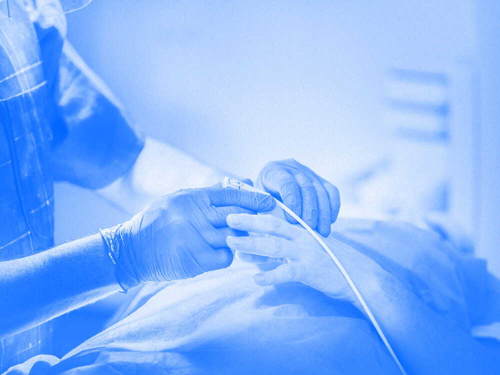 A technician places a medical device on a patient’s finger.