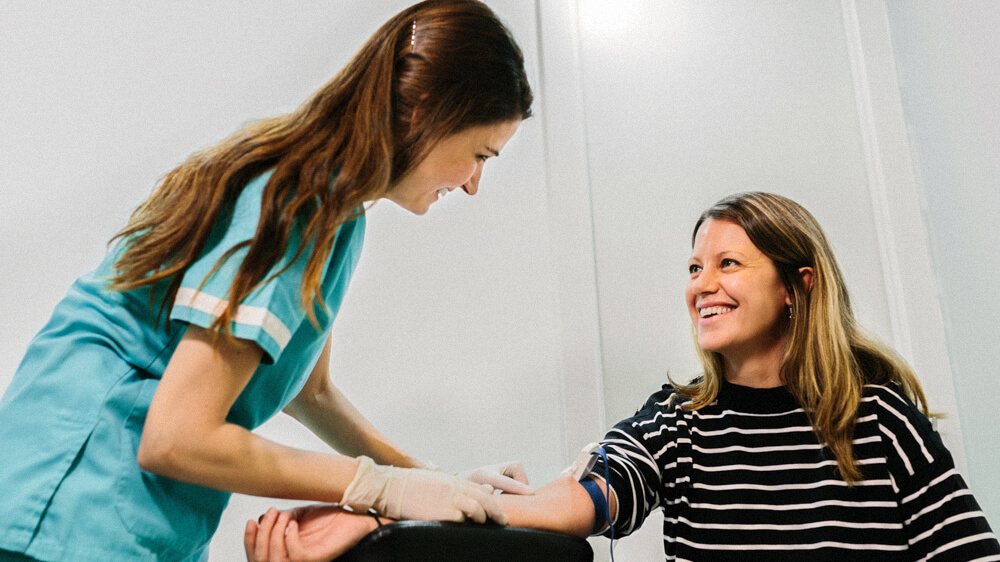 A technician feels the veins on a person’s outstretched arm.