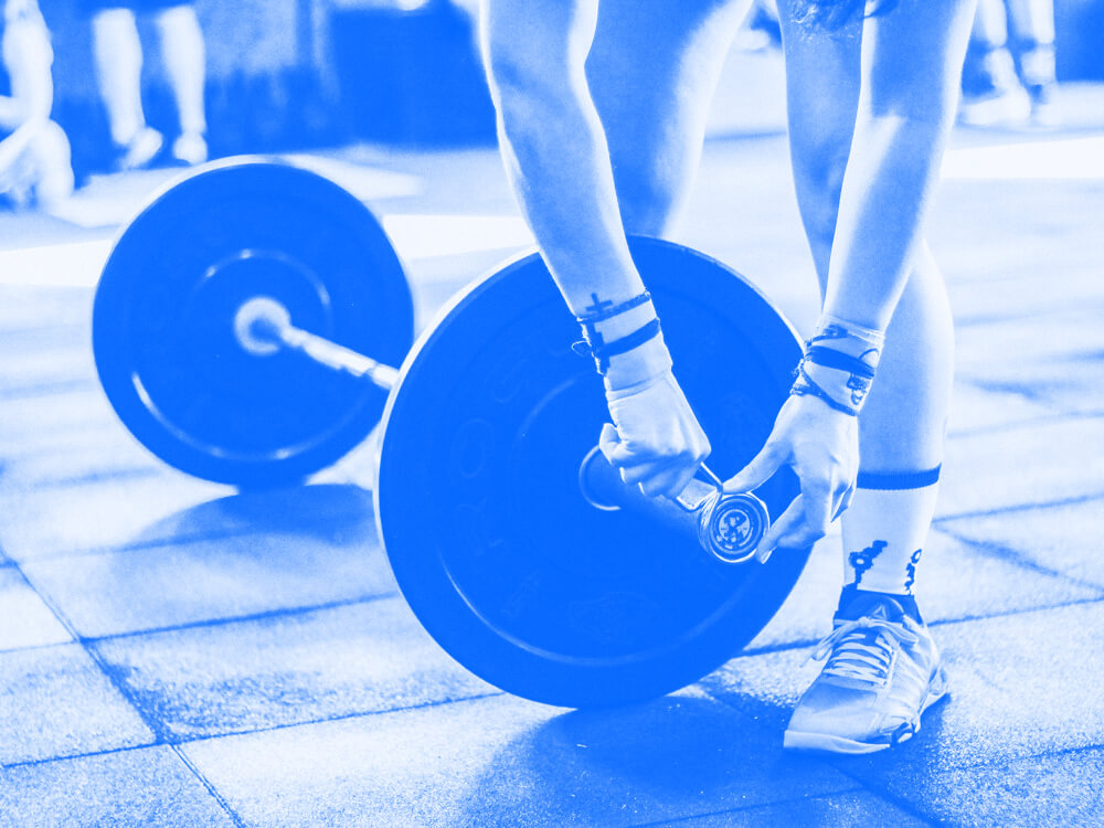 A person secures weights on a barbell with a spring clip.