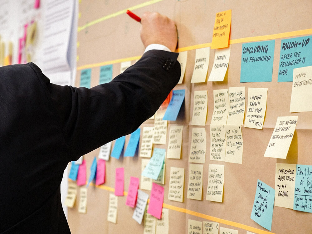 A person adds notes to a wall full of sticky notes.