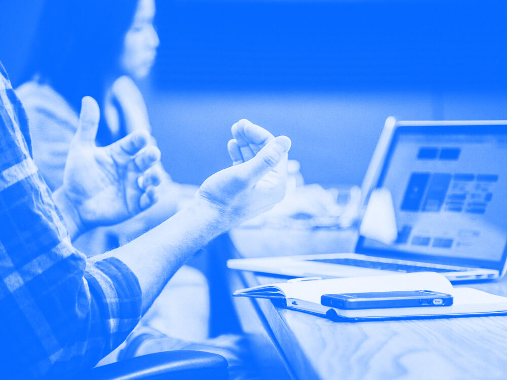 An employee sits in a meeting and talks with their hands.