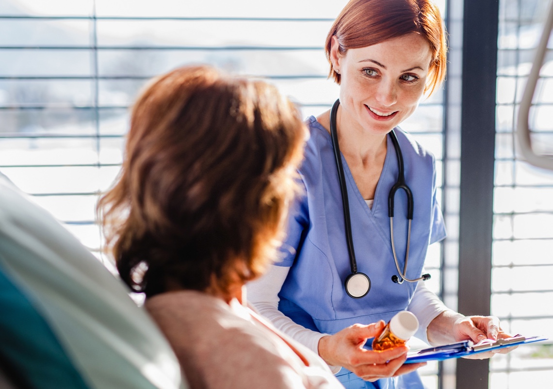 A nurse measures medication from a vial with a syringe.