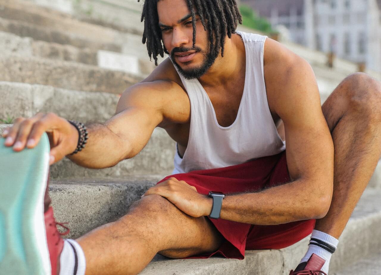 A person stretches their hamstring by pulling on their toes while seated.