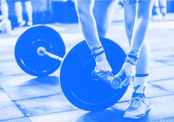 Person putting clips on the end of a barbell with weight plates.