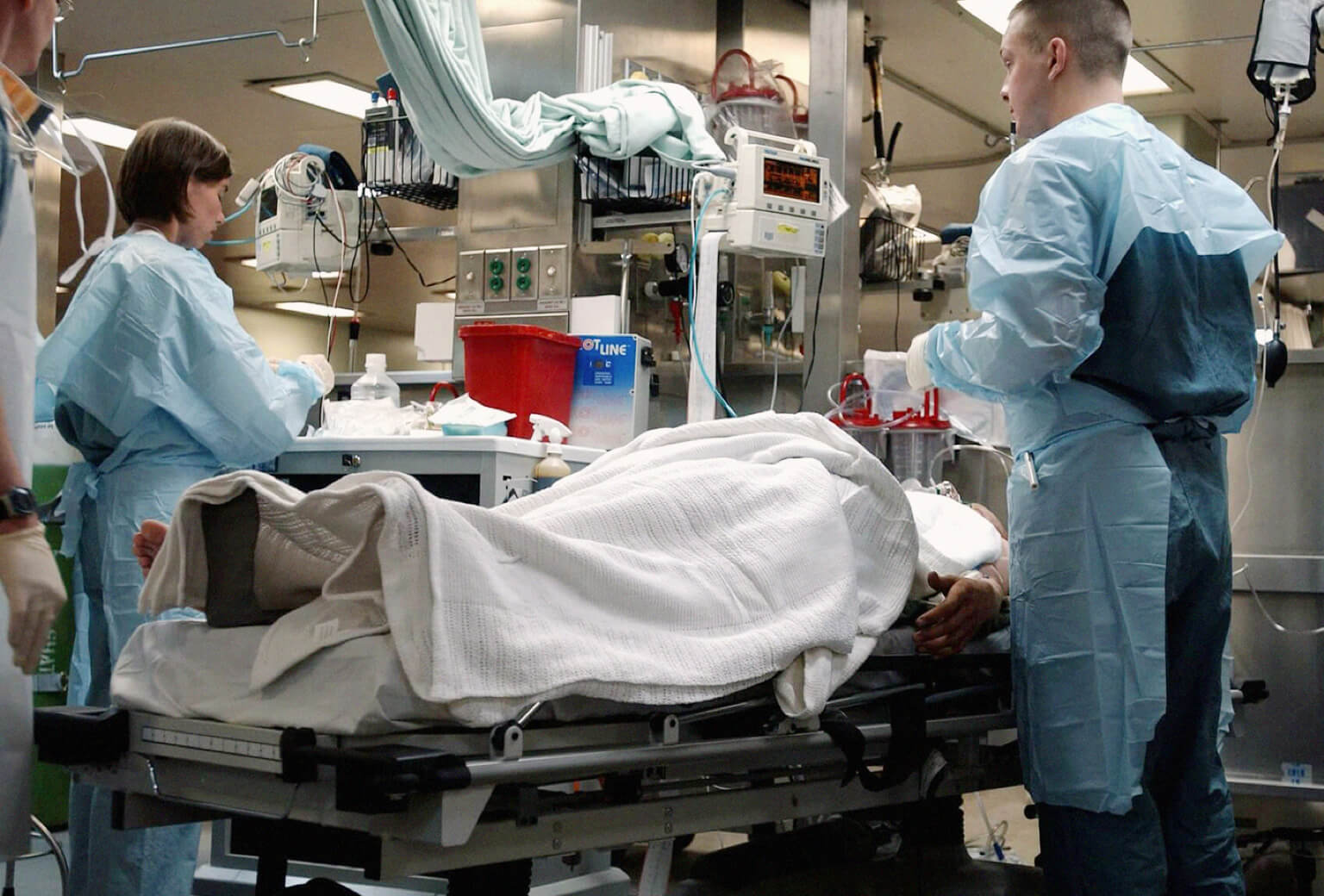 Two trauma nurses treat a patient lying on a gurney in a hospital.