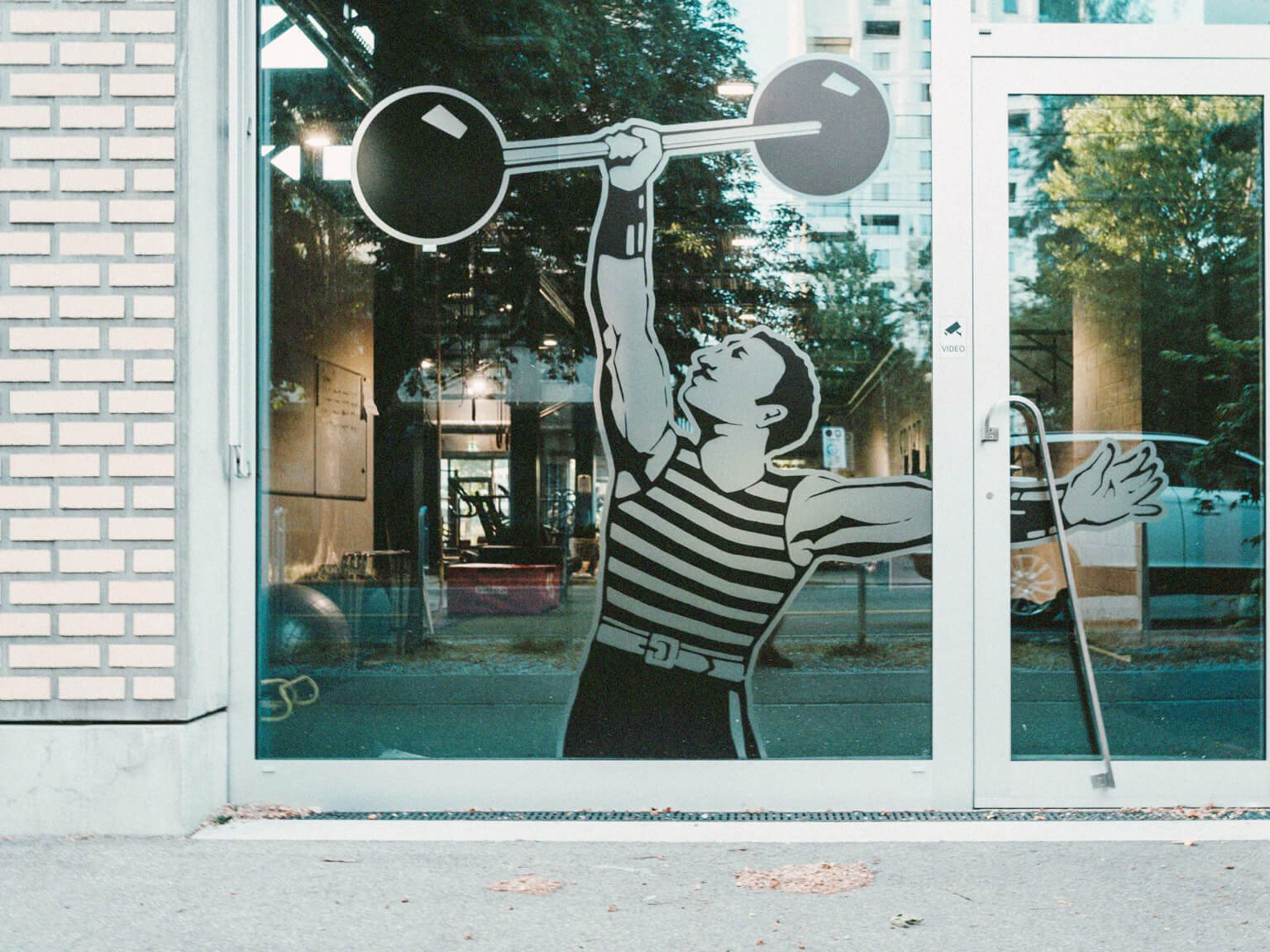 Exterior of gym with vintage window decal of person holding a retro weight.