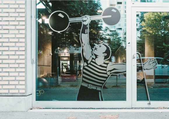 Exterior of gym with vintage window decal of person holding a retro weight.