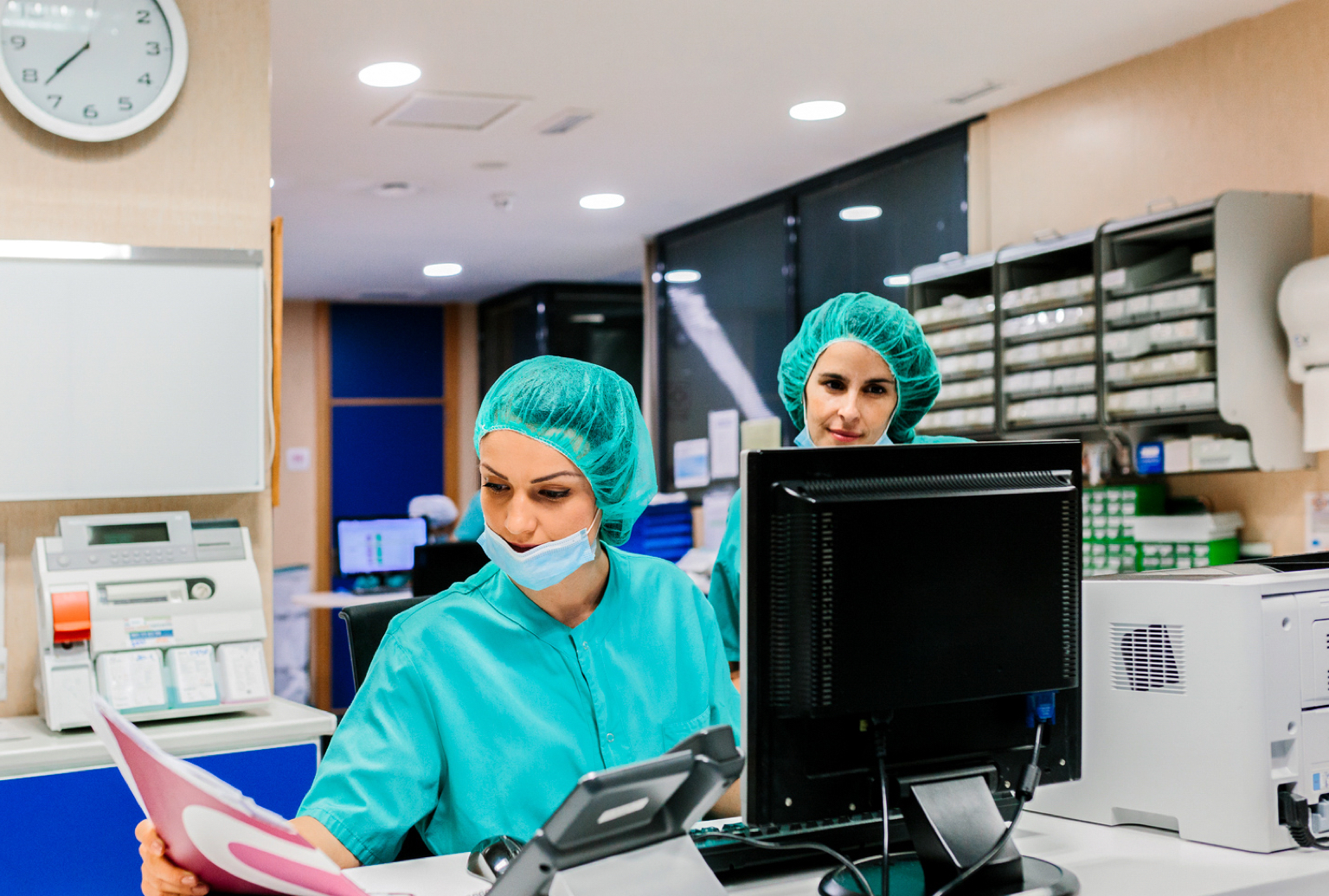 Two certified professional coders work at a computer in a medical setting.