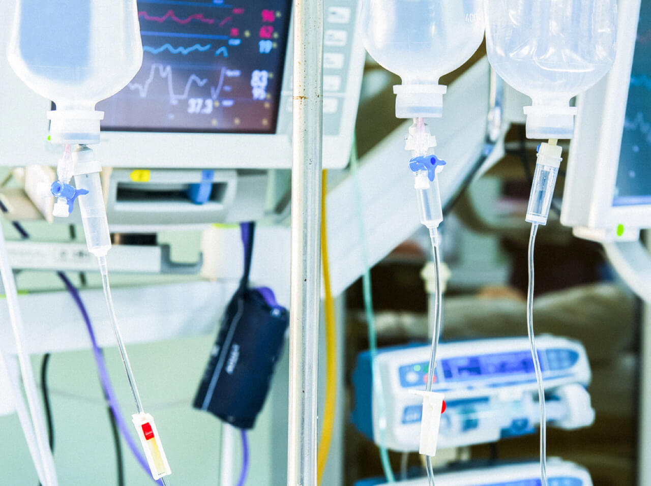 IV bags and heart rate monitor in a hospital setting. Close-up.