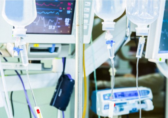 IV bags and heart rate monitor in a hospital setting. Close-up.