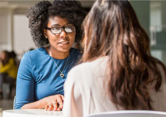 Psychologist sitting at a table talking to a colleague.