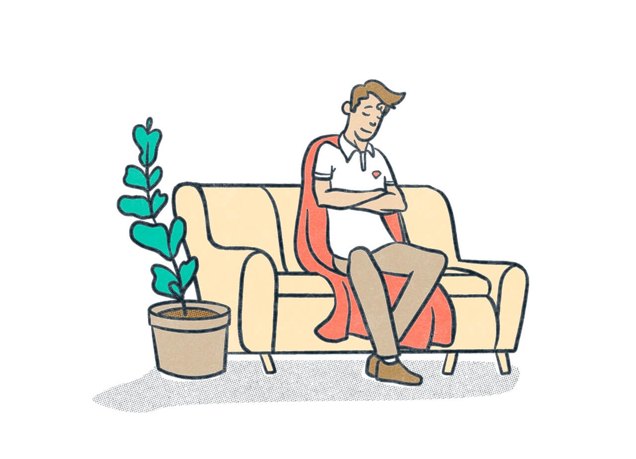 A person wearing a cape resting comfortably on a couch next to a plant.